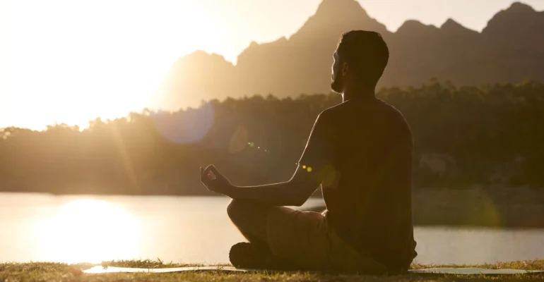 man-meditating-doing-yoga-by-lake-and-mountains-at-2023-03-17-18-02-48-utc-scaled